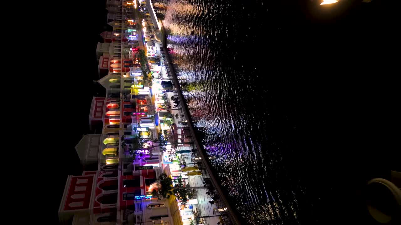 Phu Quoc: Vertical View Of Adult Woman On A Bridge In Grand World At Night With Illuminating Buildings At Background In Kien Giang, Vietnam. aerial, flyby shot