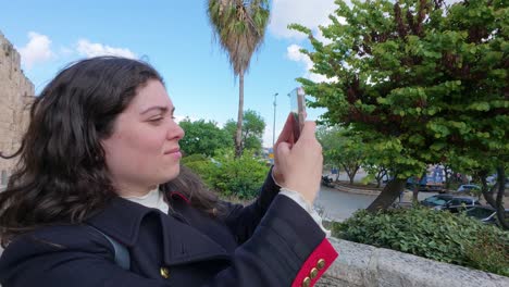 woman taking a photo in a city park near an ancient wall