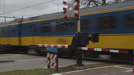 dutch train passing railroad crossing at high speed in the netherlands