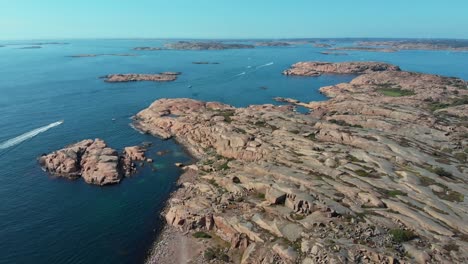 scattered rock islets in the ocean of stångehuvud and a speedboat on a sunny day - aerial shot