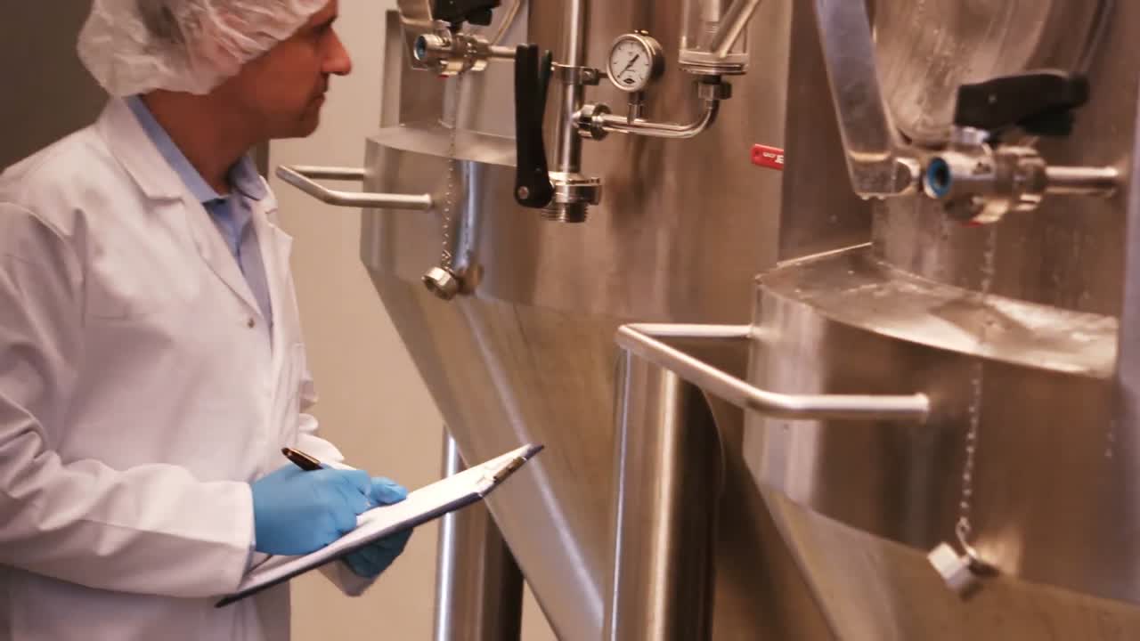 cervecero manteniendo un registro en el clipboard en la fábrica de cerveza