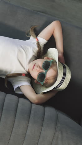 preschooler girl lies on couch near brother playing with airplane toy in hotel room. children on summer vacation in resort upper close view