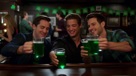 friends toasting with green beer in a bar on st. patrick's day
