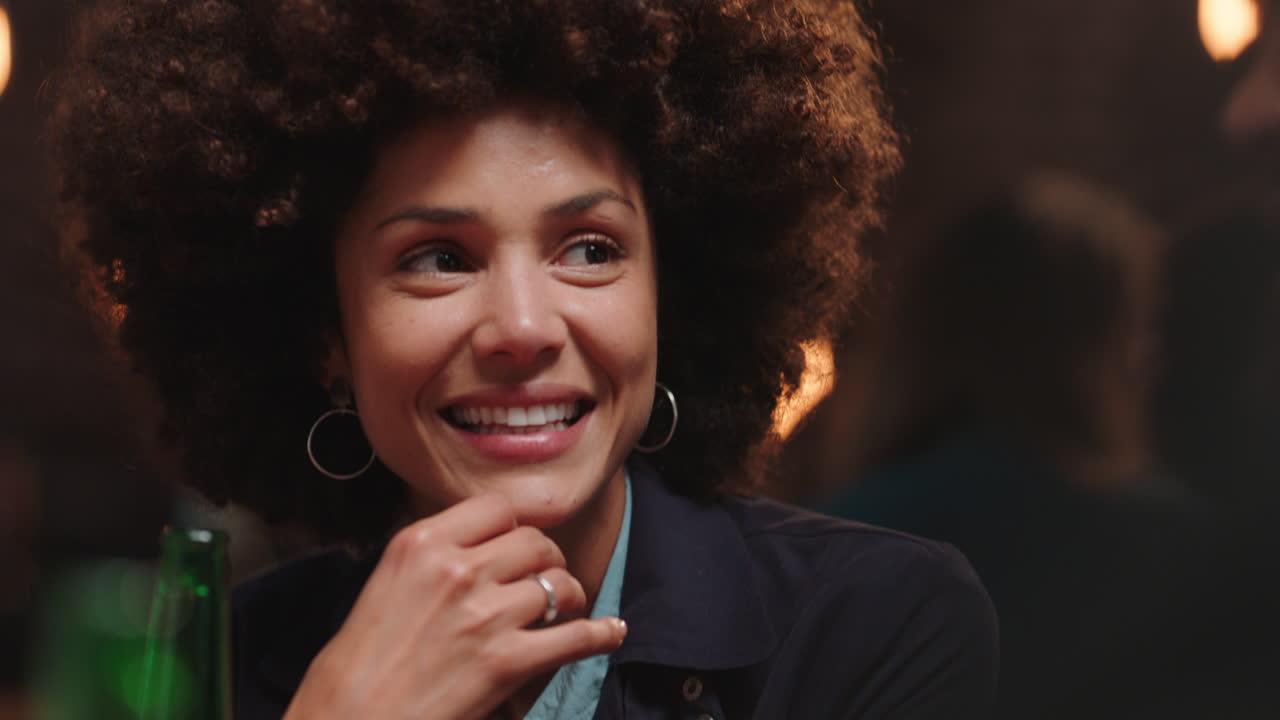 hermosa mujer con peinado afro pasando el rato con amigos en un restaurante riendo disfrutando de la conversación socializando en una reunión de fiesta