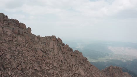 dolly in over rocky cliff revealing valley filled with wildfire smoke