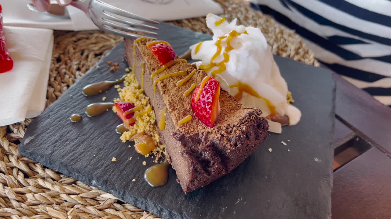 mujer comiendo pastel de chocolate con fresas y helado en un restaurante