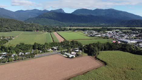 4K Drone footage of a large sugarcane farm near a small rural town with mountains in the background in North Queensland, Australia