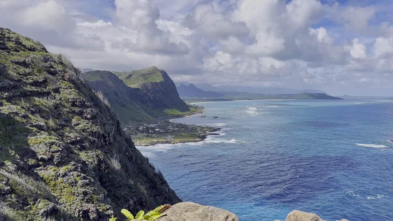 Ampia inquadratura di un panorama montano con acqua oceanica di un blu profondo che si estende fino al primo piano