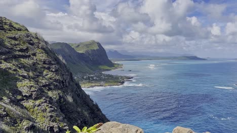 a wide shot of a mountain view with deep blue ocean water that stretches to the foreground