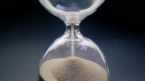 Concept-of-turning-back-time.-Hourglass-with-grains-of-sand-on-a-dark-background.