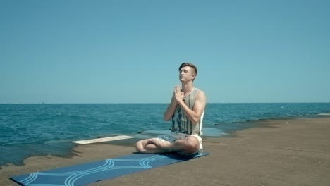 man sitting by sea in lotus position then standing on his head. man doing yoga