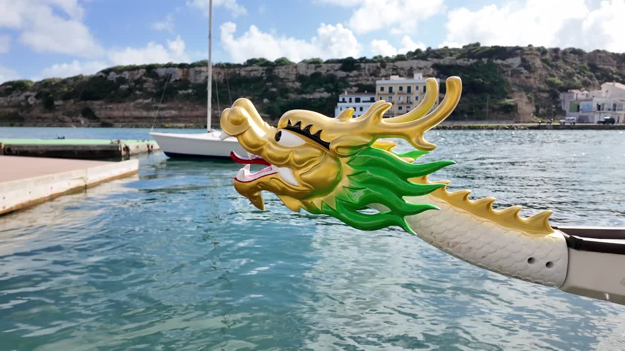 Close-up view of a dragon figurehead in a rowboat in pristine sea water and idyllic seascape in Menorca Island, Spain, in a summer morning. 4K