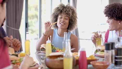 eating fries and drinking soda, diverse friends enjoying meal together at table