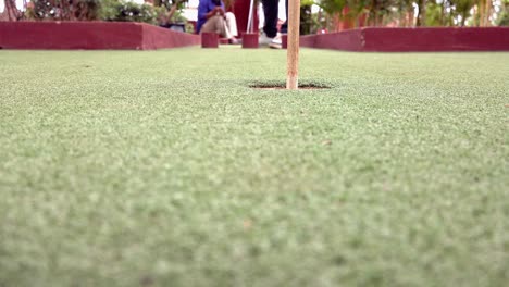 close and low shot of a golf ball being putted into the hole at mini golf