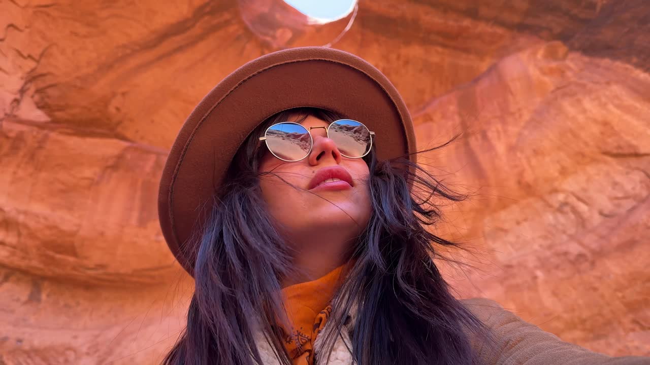 Giovane donna con cappello e occhiali da sole in posa nel Red Rock Canyon