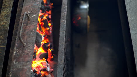 slow motion of red hot burning charcoal with flames in a rusted restaurant grill