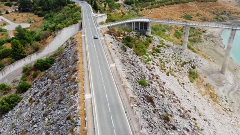 Toma-Aérea-Siguiendo-El-Coche-En-La-Carretera-Por-Encima-Del-Sistema-Hidráulico