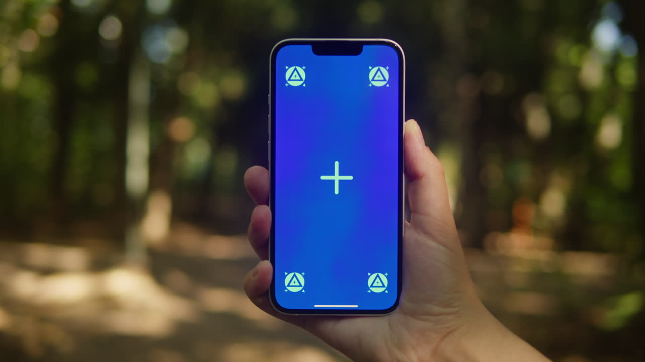 Young woman holding phone chroma key screen in the lovely park close-up. Girl with green screen on smart phone. Nature.