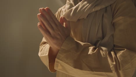 close up shot of man wearing robes with long hair and beard representing figure of jesus christ praying