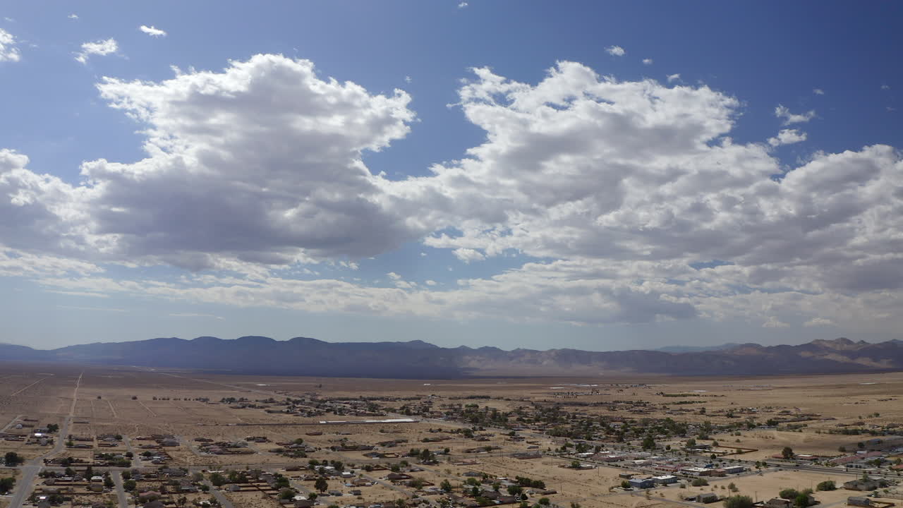 una ciudad en expansión en la cuenca del desierto de mojave con montañas en la distancia - vista aérea