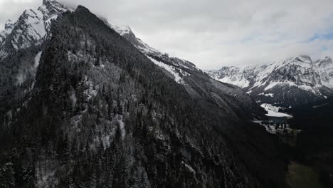 Snow-capped,-majestic-Swiss-Alps-mountains,-situated-near-Glarus,-Switzerland,-captured-in-a-wintertime-aerial-view-under-a-cloudy-and-misty-sky