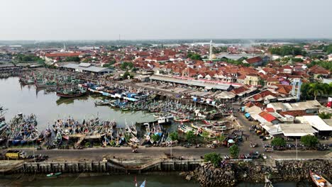 El-Ajetreo-Y-El-Bullicio-Del-Puerto-Pesquero-Más-Grande-De-Java-Están-Llenos-De-Barcos-Tradicionales-Que-Bordean-Los-Muelles,-Yuxtapuestos-A-La-Zona-De-Pesca-Industrial-Y-Al-Pueblo-Densamente-Poblado.