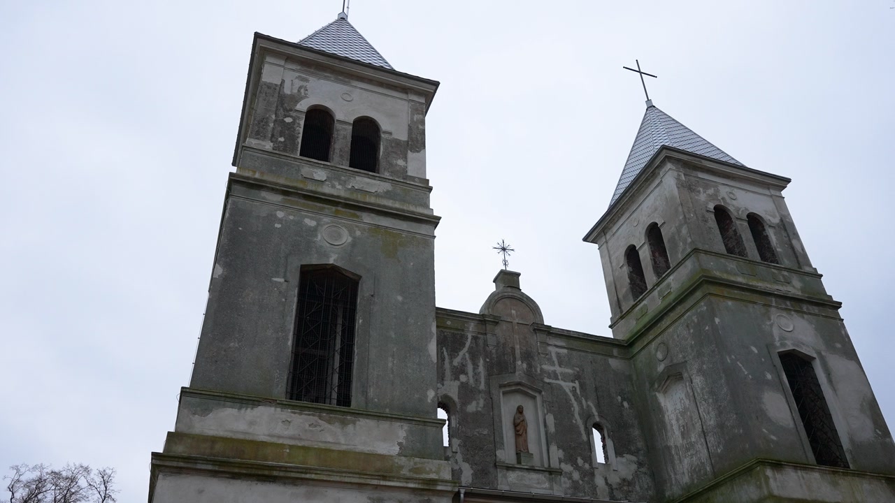 Capture of a historic church with twin towers, rustic architecture, set against a cloudy sky. The imposing facade and weathered details offer a sense of timeless grandeur.