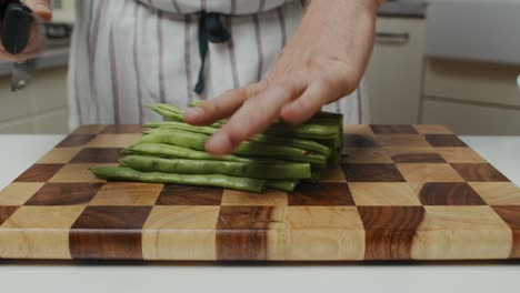 el chef corta las verduras con un cuchillo de cocina en una tabla cortada de madera en la mesa de la cocina