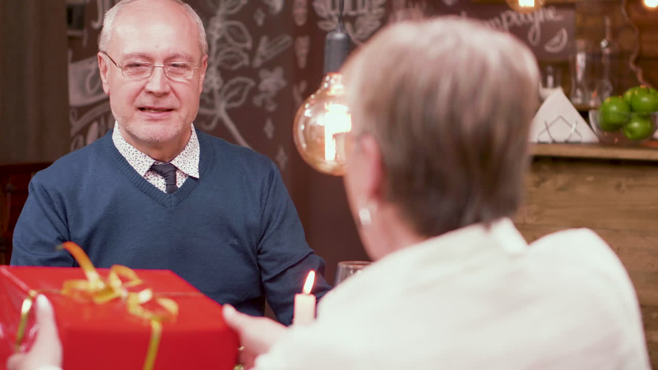 Elderly couple celebrates anniversary with a surprise gift at a restaurant