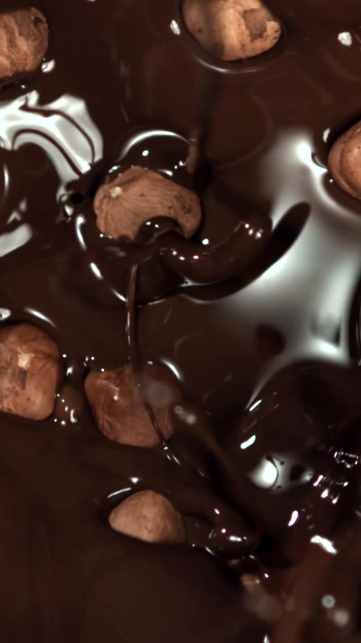 Cioccolato fuso che cola sulle nocciole al rallentatore