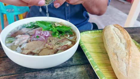 squeezing lime over a bowl of pho bo or traditional vietnamese beef noodle soup, authentic local food from vietnam