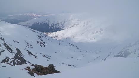 Legs-and-feet-of-climber-resting-on-edge-of-snow-covered-mountain-peak