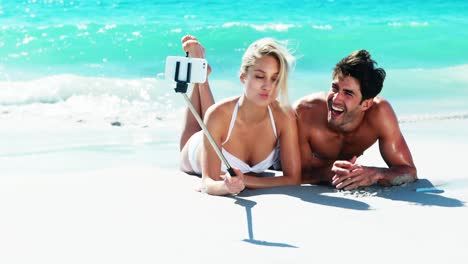 Pareja-Tumbada-En-La-Playa-Y-Tomando-Un-Selfie-Desde-El-Teléfono-Móvil