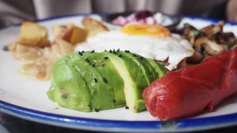 breakfast plate with avocado, eggs, and sausage