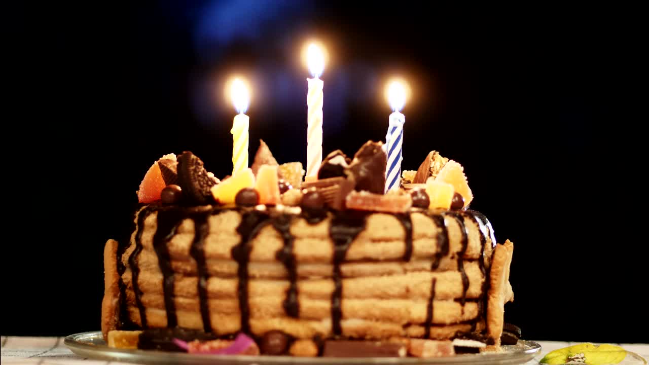 Torta di compleanno in una stanza buia con tre candele.