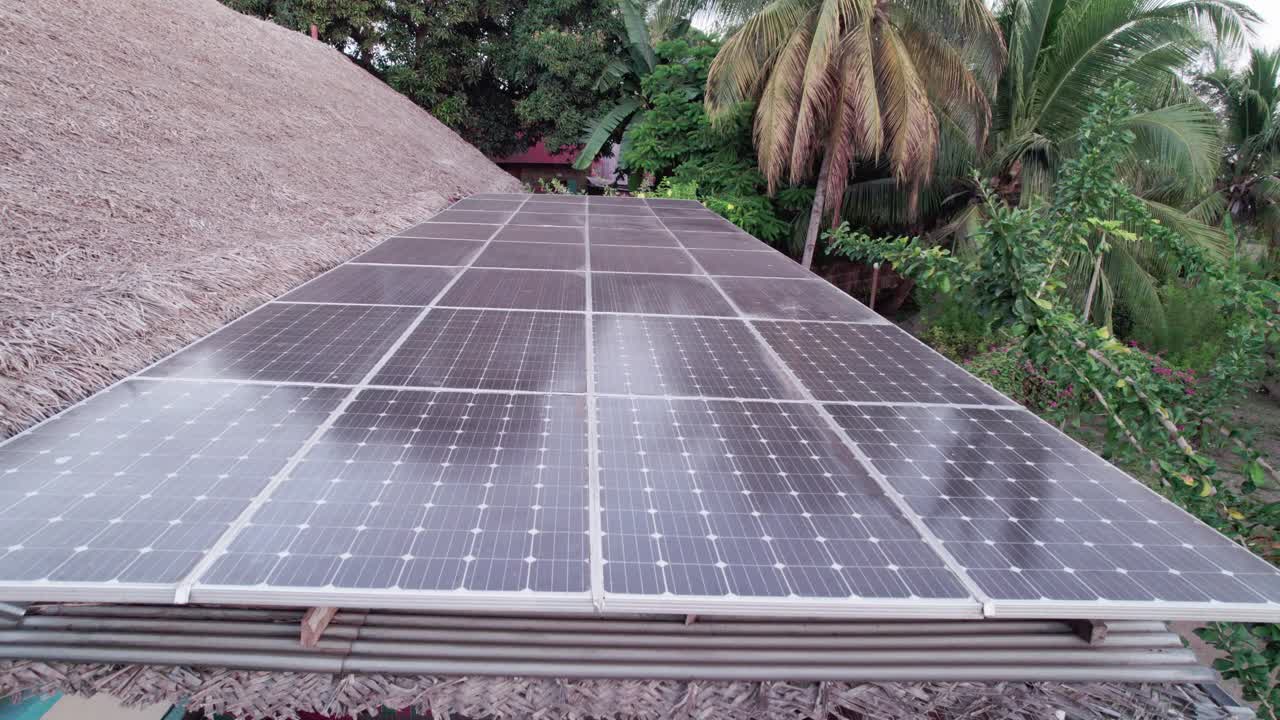 paneles solares de cerca junto al techo de reet en un entorno rural, reflejo de los árboles