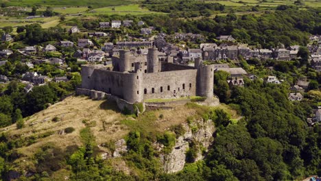 Harlech-castle-in-North-Wales,-Gwynedd,-UK,-shot-by-drone-to-show-proximity-of-the-castle-against-the-town-and-coast