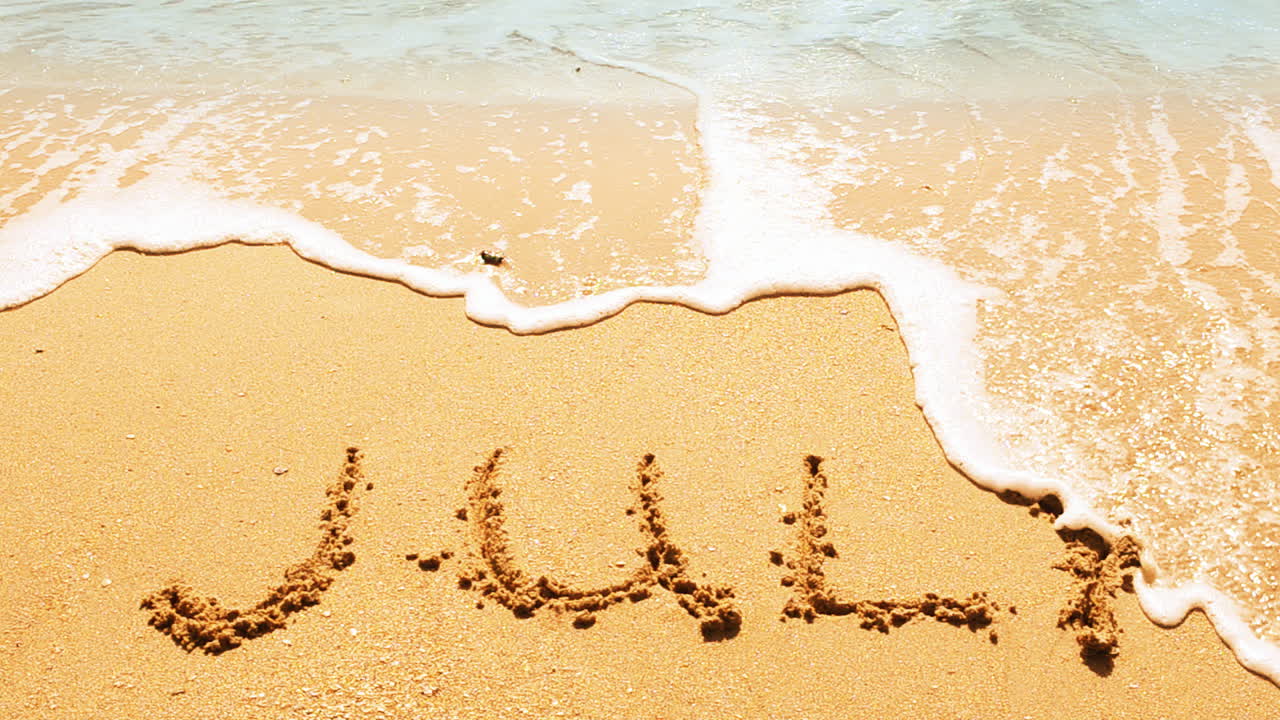 Inschrift des Monatsnamens im Sand, am Strand. Aufnahme am Strand.