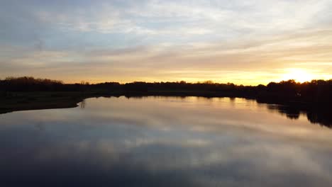 Relaxing-landscape-with-lake-water-and-golden-sunset-in-Belgium,-aerial-drone-view