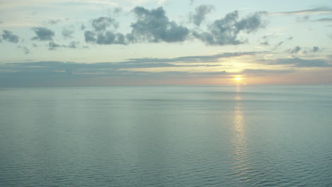 Puesta-De-Sol-En-El-Mar-En-Calma-Con-Algunas-Nubes-Pequeñas