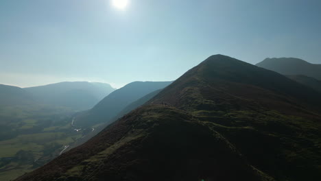 Hikers-on-distant-hillside-with-slow-orbit-revealing-green-valley-and-misty-mountains-in-English-Lake-District-UK