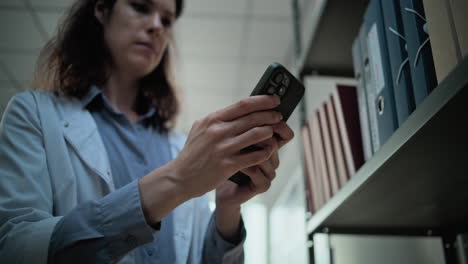 médico usando un teléfono inteligente en una biblioteca