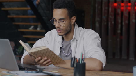 young man reading a book at a wooden desk