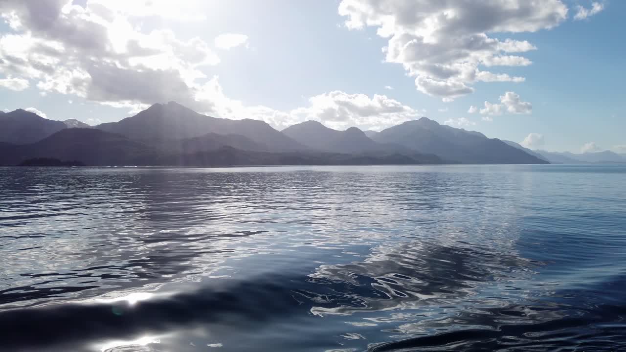 Mountains of Patagonia and sunbeams from smooth calm lake boat cruise
