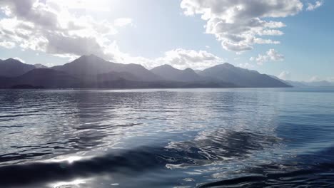 mountains of patagonia and sunbeams from smooth calm lake boat cruise