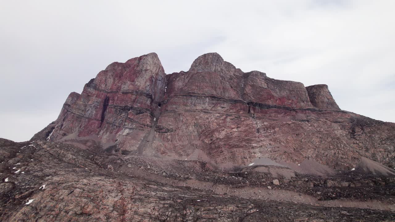 A flight over a landscape carved by ancient glaciers. Witness the raw geology of Greenland's mountains rising from the deep, clear channel of the Uummannaq Fjord