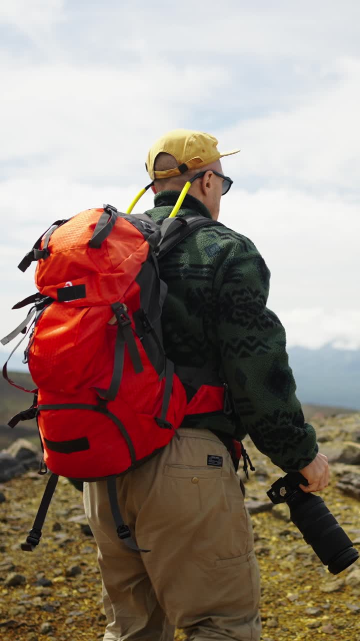 Escursionista con zaino e macchina fotografica che cammina su un sentiero di montagna
