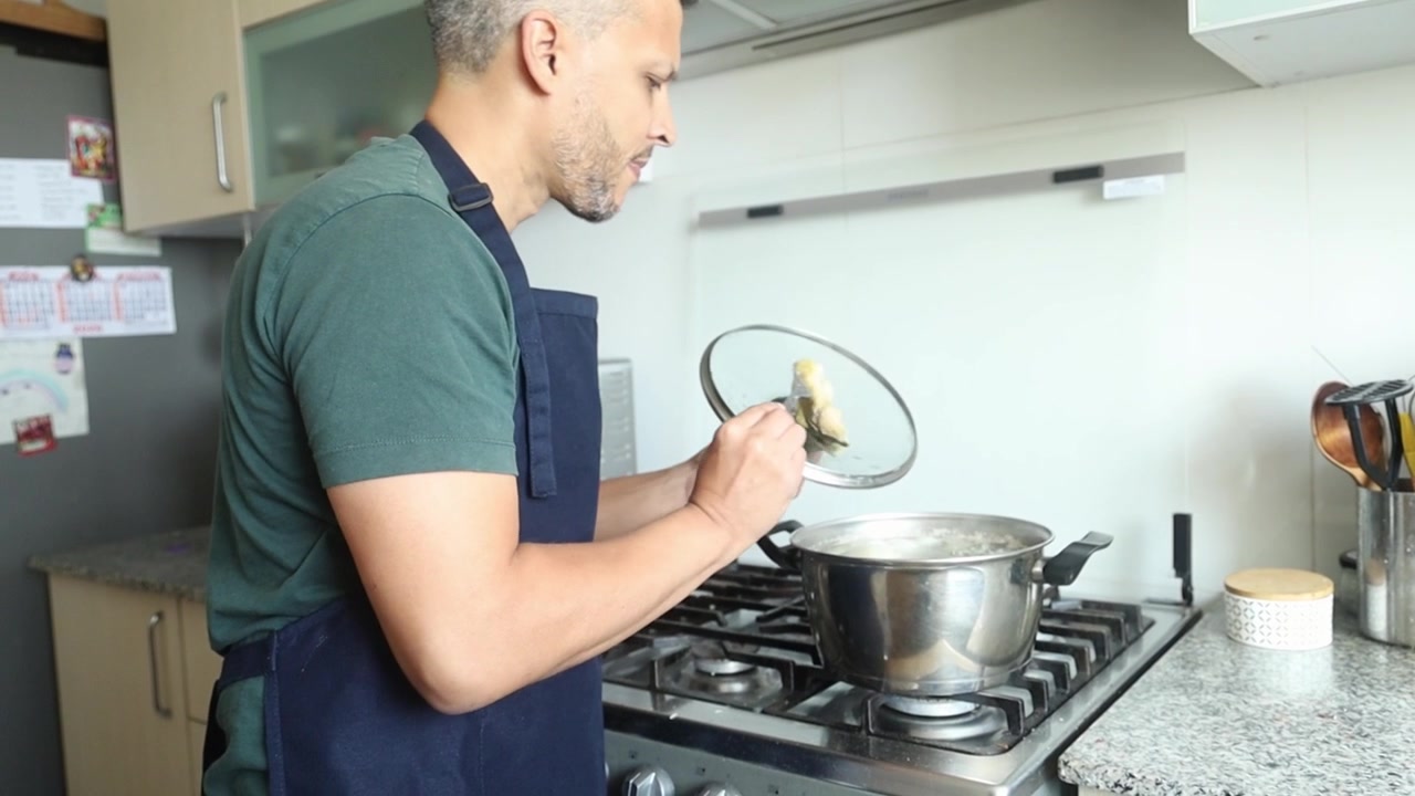 Pria Bercelemek Memasak Makanan di Dapur Rumah