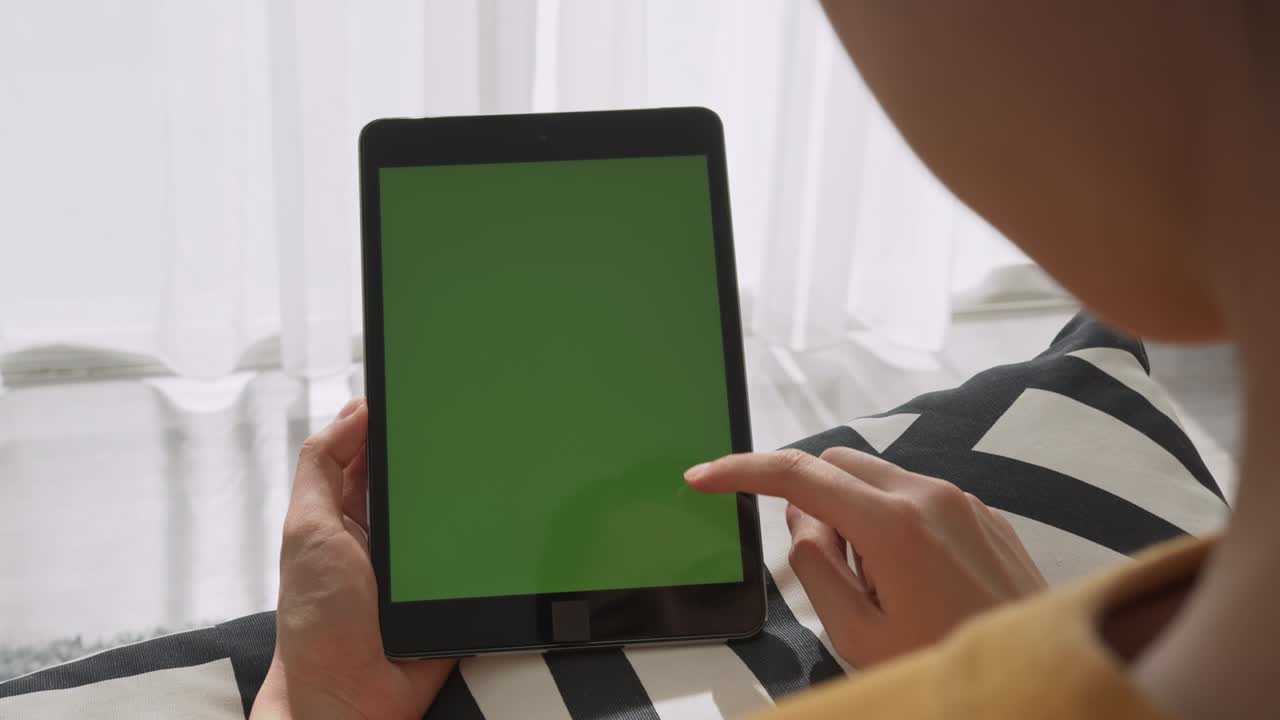 mujer sosteniendo una tableta digital con pantalla verde y dispositivo táctil navegando por internet.