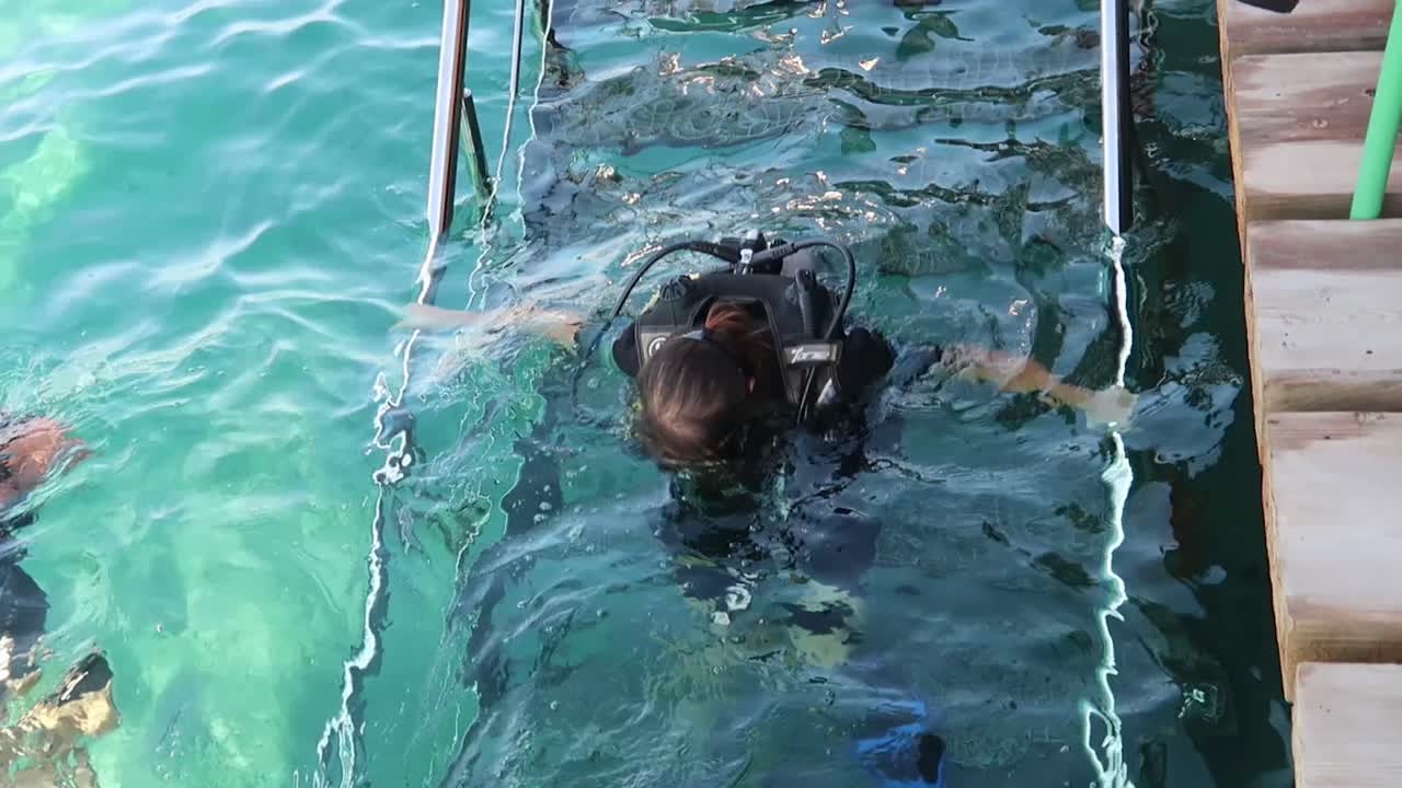 fotografía en cámara lenta de una mujer comprobando que su equipo de buceo está seguro y seguro